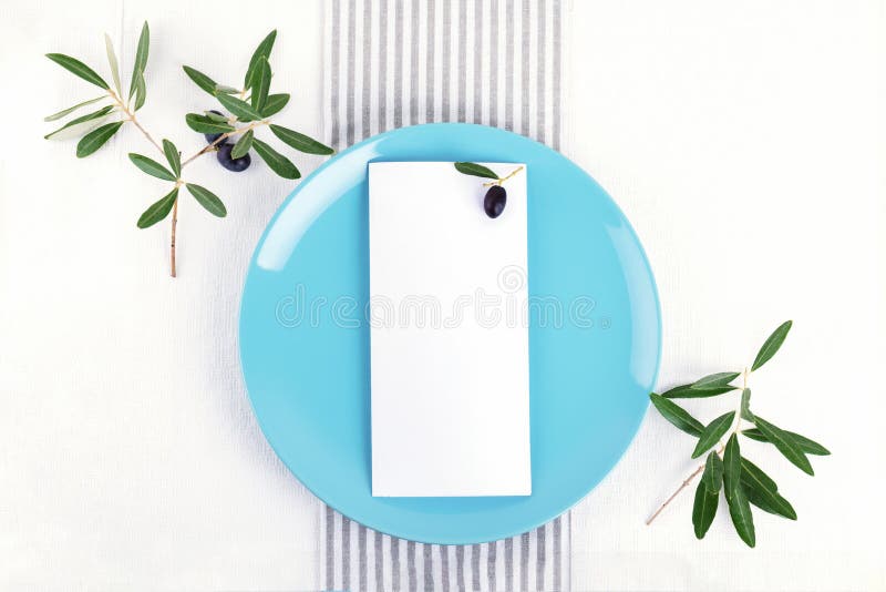 Festive wedding, birthday table setting with golden cutlery, olive branch, pastel blue porcelain plate. Blank card mockup. stock photo