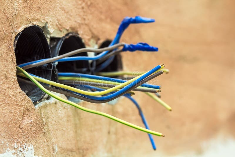 Finishing works at renovated apartment. Electrical wiring installation. Electrical exposed wires protruding from socket on old wa royalty free stock photo Finishing works at renovated apartment. Electrical wiring installation. Electrical exposed wires protruding from socket on old wa royalty free stock photo