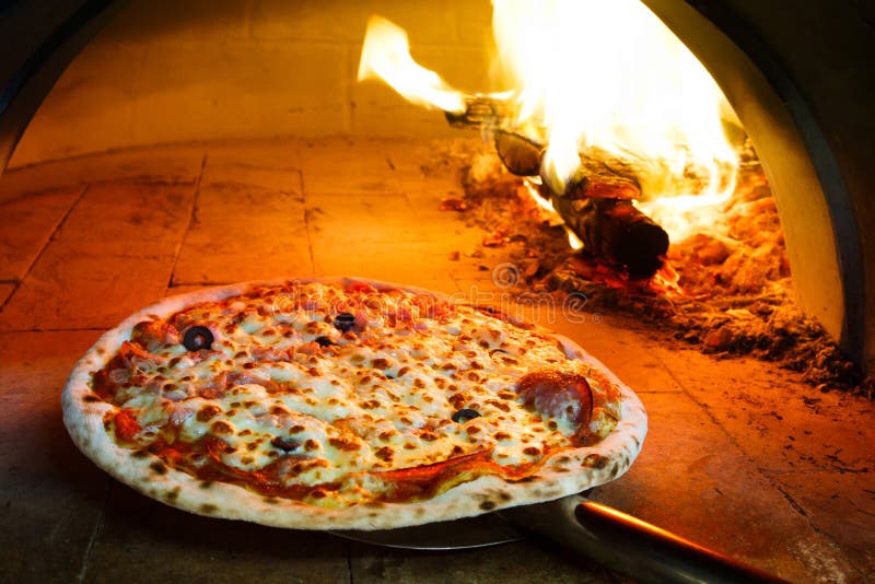 Firewood oven pizza. Close up pizza in firewood oven with flame behind royalty free stock images Firewood oven pizza. Close up pizza in firewood oven with flame behind royalty free stock images