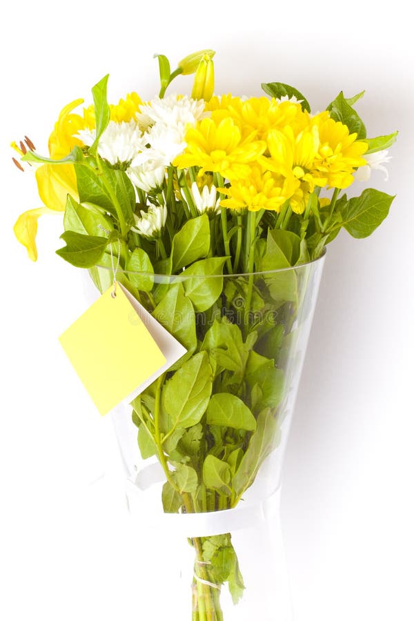 Flowers in a glass vase. Bunch of freshly cut white carnation flowers, yellow liliums and yellow carnations arranged in a simple floral bouquet in a glass vase royalty free stock images