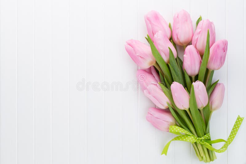 Fresh pink tulip flowers bouquet on shelf in front of wooden wall. stock photos