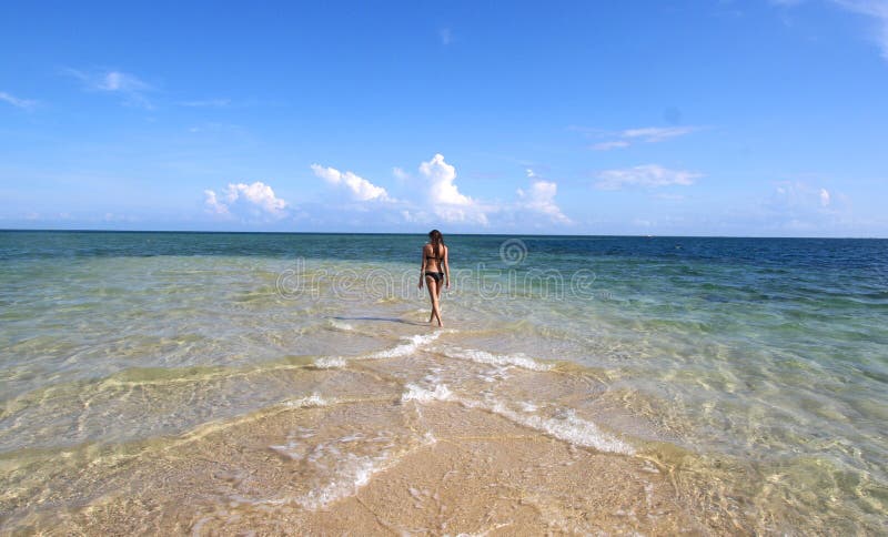 Girl in black bikini walking on the white beach royalty free stock photography