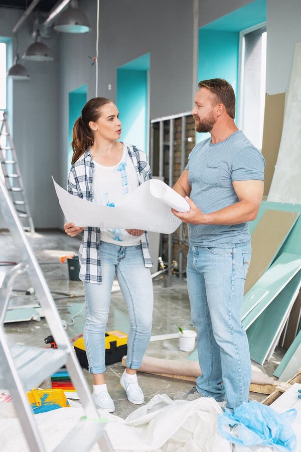 Serious man discussing renovations with a woman. Good suggestion. Determined muscular men holding a sketch and discussing renovations with a woman stock image