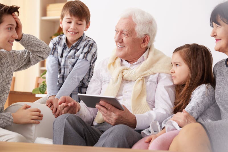 Grandchildren teaching grandpa to use a tablet royalty free stock photo