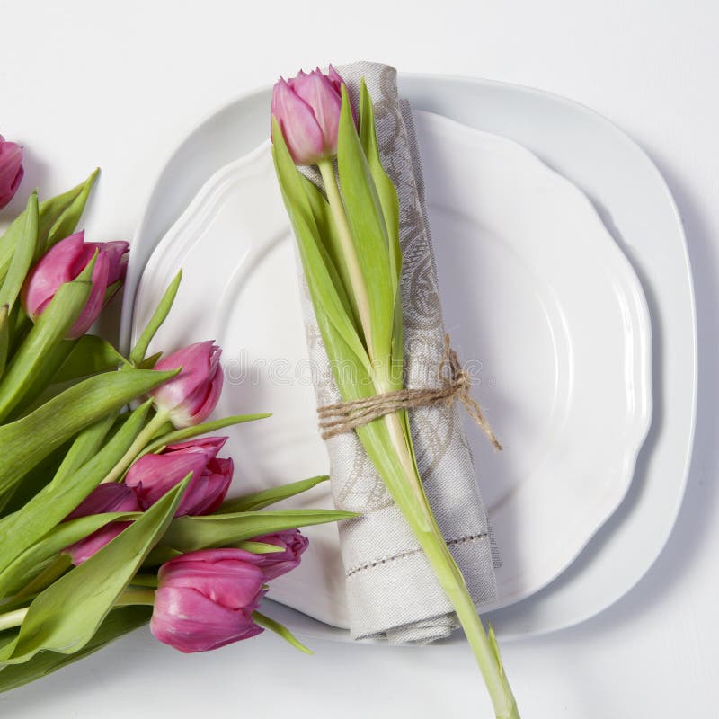 Greeting card for Valentine`s day. Decoration of the wedding table. On a plate a napkin with a tulip, beautifully tied. stock photo