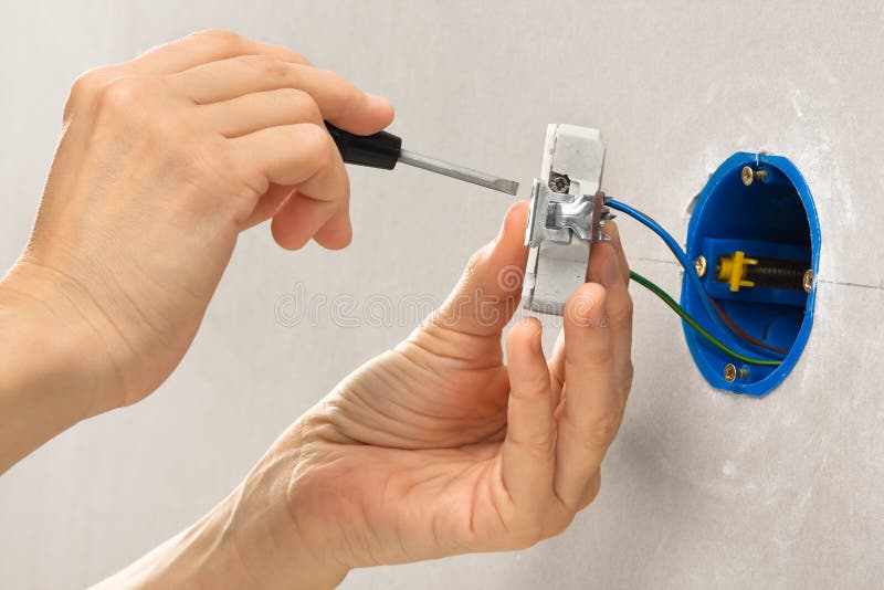 Hands installing electrical wall socket with screwdriver royalty free stock photo