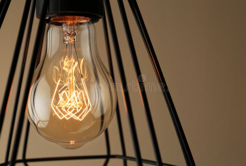 Hanging lamp bulb in chandelier against beige background. Closeup stock image