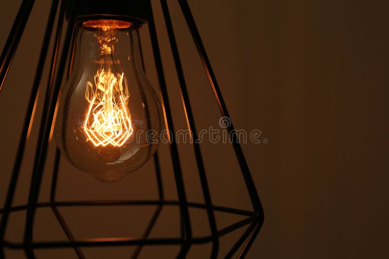 Hanging lamp bulb in chandelier against brown background. Closeup royalty free stock photo