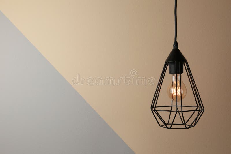 Hanging lamp bulb in chandelier, space for text. Hanging lamp bulb in chandelier against color background, space for text royalty free stock images