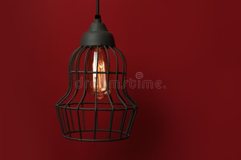 Hanging lamp bulb in chandelier against dark red background. Space for text royalty free stock photos