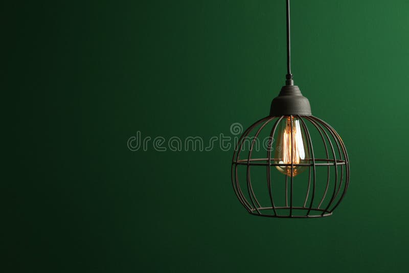Hanging lamp bulb in chandelier against green background. Space for text stock photos