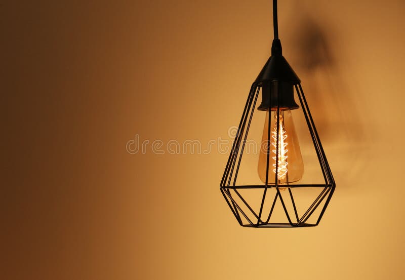 Hanging lamp bulb in chandelier against yellow background. Space for text stock photo