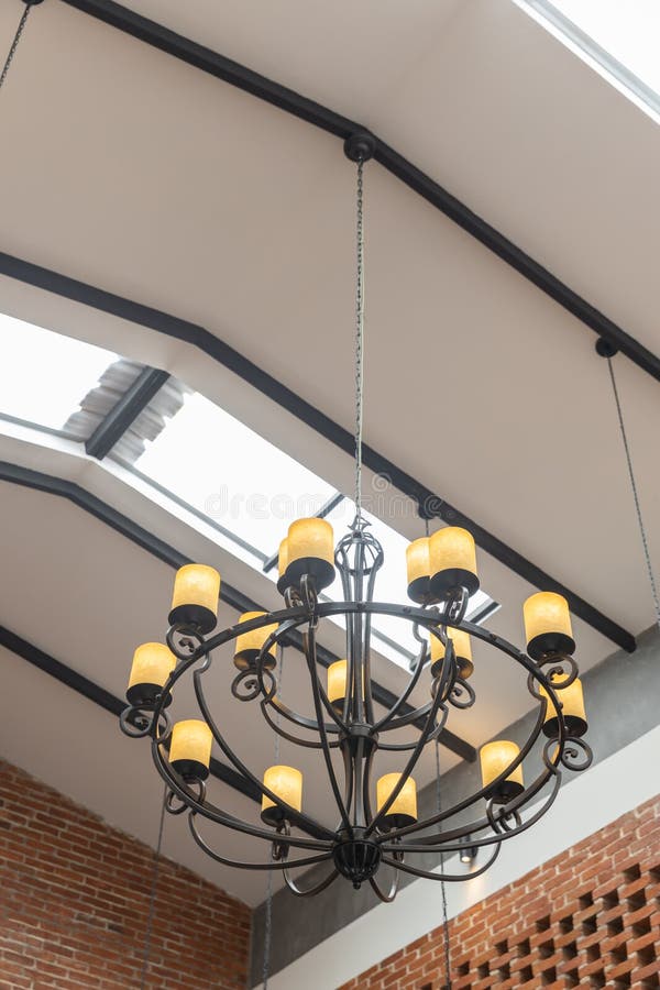 Hanging vintage black Chandelier ceiling with yellow lamp and brick wall interior. At day light royalty free stock photos