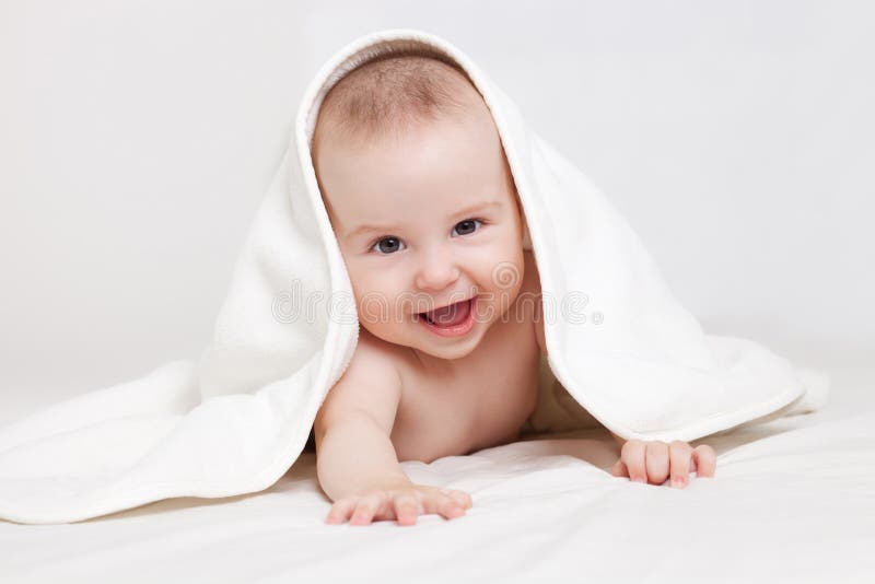 Happy baby under white blanket stock photography