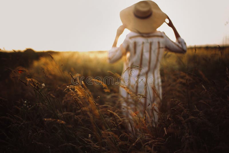 Herbs and grasses in sunset light on background of blurred woman in summer meadow. Wildflowers close up in warm light and rustic. Girl relaxing in evening in royalty free stock photos