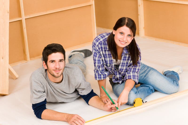 Home improvement young couple work on renovations. Home improvement young happy couple working on floor renovations royalty free stock photos
