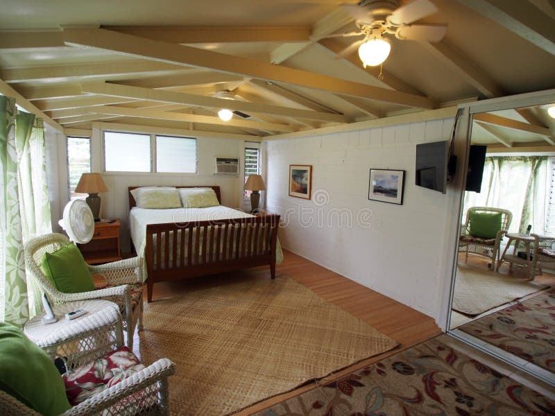 Inside Cottage Bedroom. With Queen bed, Mounted HDTV, White Wicker chairs and bathroom stock photos