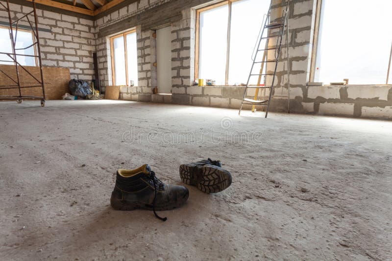 Interior of apartment during under renovation, remodeling and construction a pair of working shoes on the cement floor stock photos