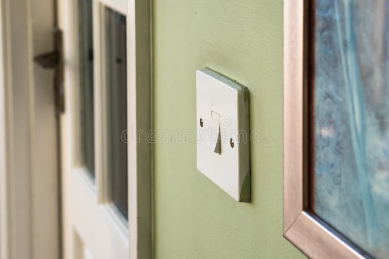 Isolated image of an interior light switch in the off position. Seen next to a small wall painting and an interior wooden door leading to a utility room royalty free stock images