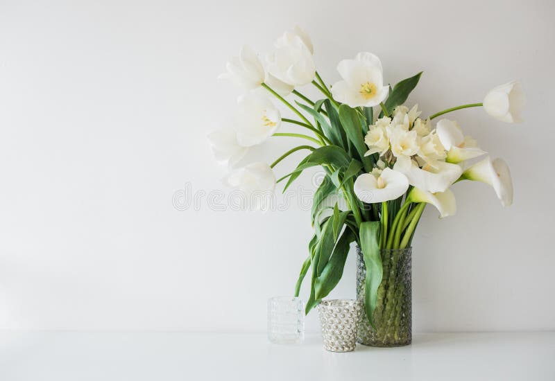 Large bouquet of white spring flowers in a vase, daffodils, tuli. Ps and feces in home interior decor royalty free stock photos