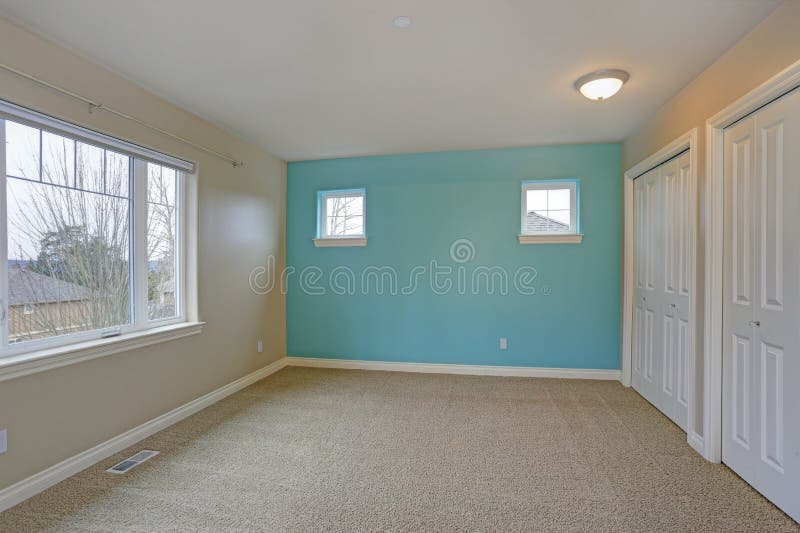 Light empty room interior with focus on a bright blue wall. Light empty room interior with accent blue wall, built in closet, carpet floor royalty free stock photography