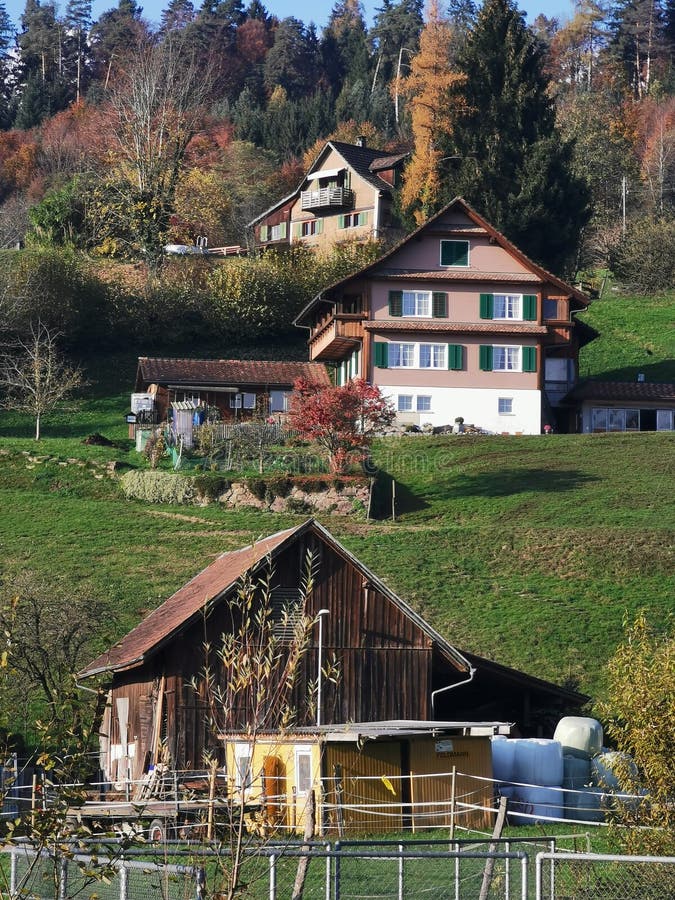 Swiss farm houses. A line up of swiss farm houses in the fall with colorful trees and green grass around. A cute small barn and hay bales are also in the scene royalty free stock photography
