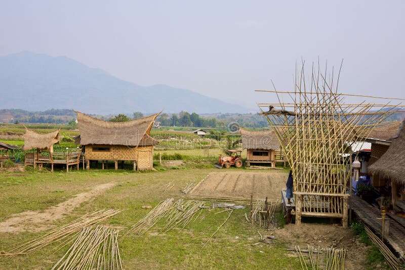 Local architectural house with unique roof design and under construction bamboo structure in foreground mountain in background. In northern region of Thailand royalty free stock photos