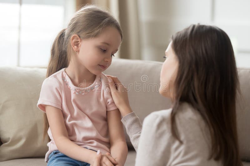 Loving mom talking to upset little child girl giving support. Loving worried mom psychologist consoling counseling talking to upset little child girl showing royalty free stock image