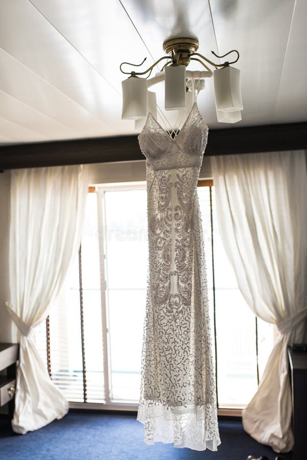 Luxury wedding dress hanging on the chandelier in a hotel room. Bridal gown. Bridesmaids. Wedding royalty free stock photography