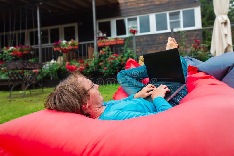 Man working on laptop on terrace, remote work in the country. Man working on laptop on summer terrace, remote work in the country stock photography