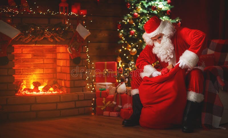 Merry Christmas! santa claus near the fireplace and tree with gi royalty free stock photo