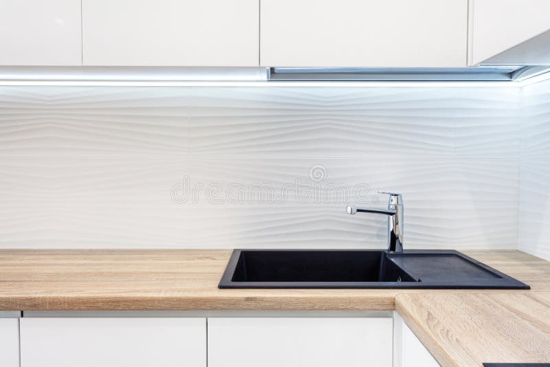 Modern designer chrome water tap over black new kitchen sink. The working area of the kitchen surface is made of wood. Table top m stock photography Modern designer chrome water tap over black new kitchen sink. The working area of the kitchen surface is made of wood. Table top m stock photography