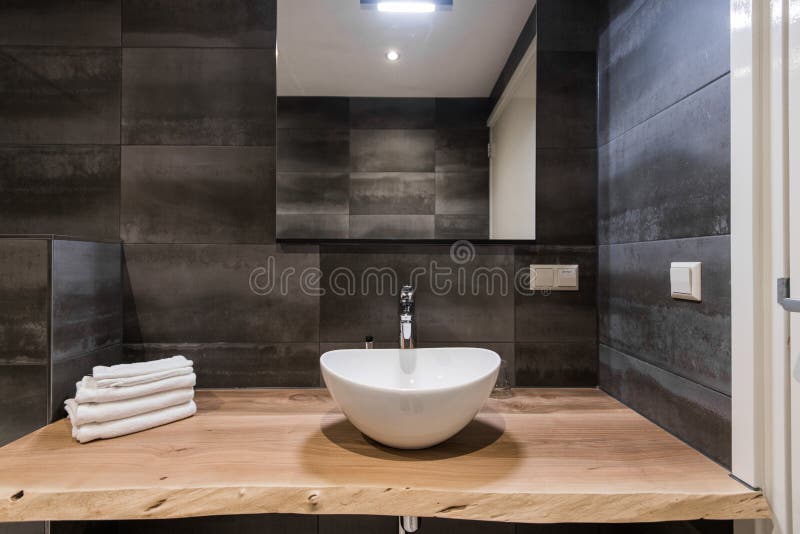 Modern interior of the bathroom. The washbasin is made of white massive shell on the table of wood. Minimalism and stock images