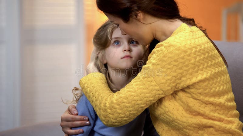 Mother hugging sad little adorable girl home after work, family love and care. Stock photo stock photography