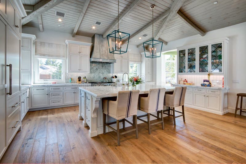 Huge bright modern home kitchen. New model home huge kitchen with white cabinetry and dining island with hardwood floors royalty free stock photos