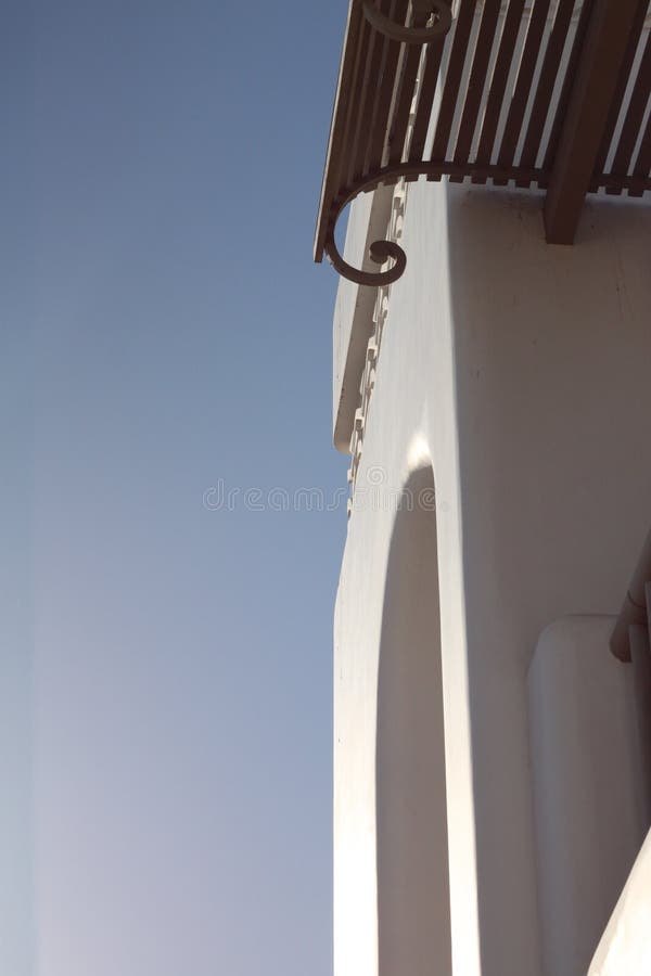 Part of the white wall with arch, balcony and canopy. Against the blue summer sky stock image