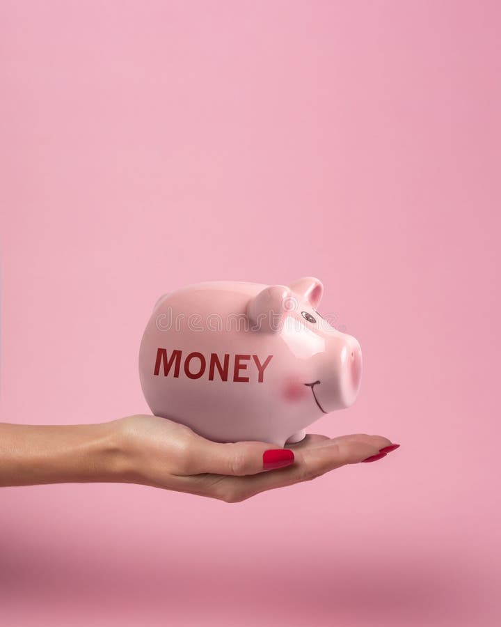 Piggy bank in a woman hand with inscription MONEY on a pink background. Minimal saving money concept royalty free stock photography