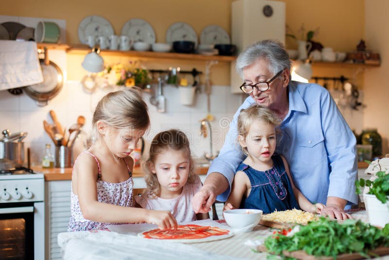Pizza cooking class for kids, children chef. Cute girls are preparing italian food. Family dinner in cozy home kitchen. royalty free stock images