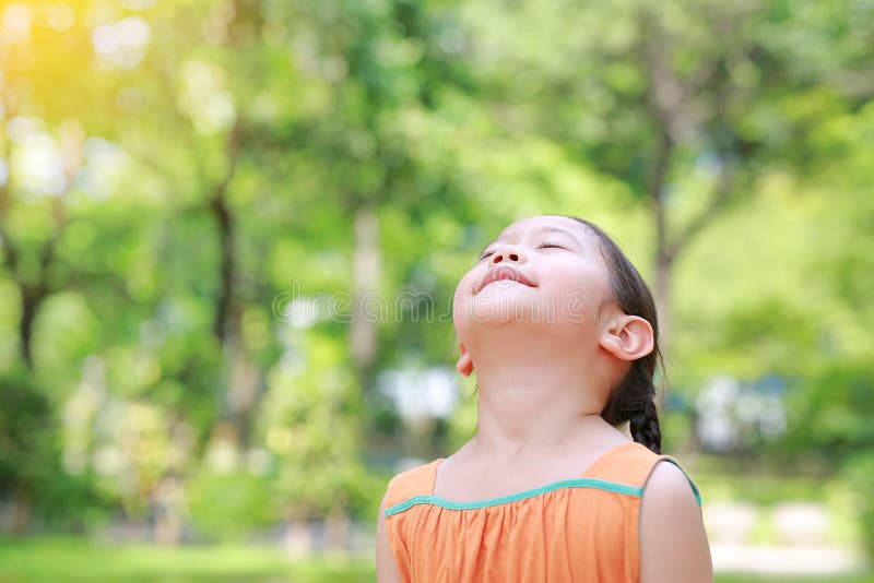 Portrait of happy Asian child close their eyes in garden with Breathe fresh air from nature. Close up kid girl relax in green park. For good health royalty free stock images
