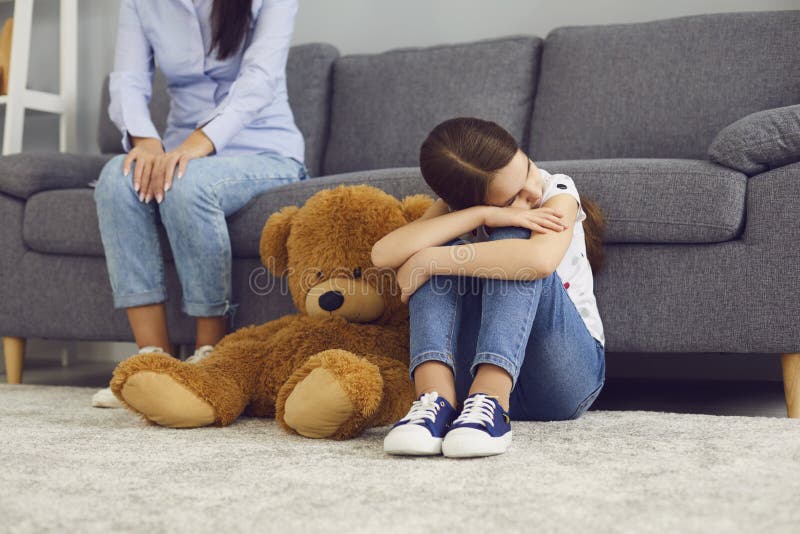 Sad offended child sitting on the floor does not talk with mother in the room. The problem is the relationship between mother and child in the family. Conflict royalty free stock photos