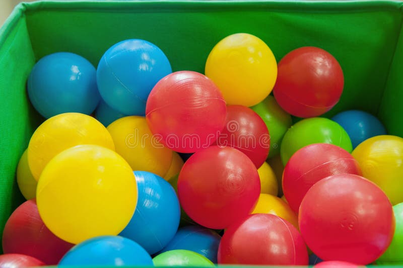 Red, yellow, blue plastic balls lie in the green box. The interior of the children`s room with lots of colorful toys. Close up royalty free stock image