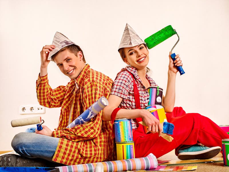 Repair family by happy couple building home. Family renovation in new apartment. Mad women and men in newspaper cap renovation apartment. Students share an stock image