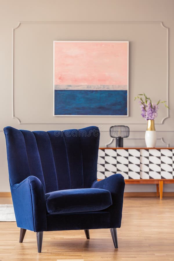 Retro, navy blue armchair in an elegant living room interior with an abstract painting on a wall. With molding stock photography