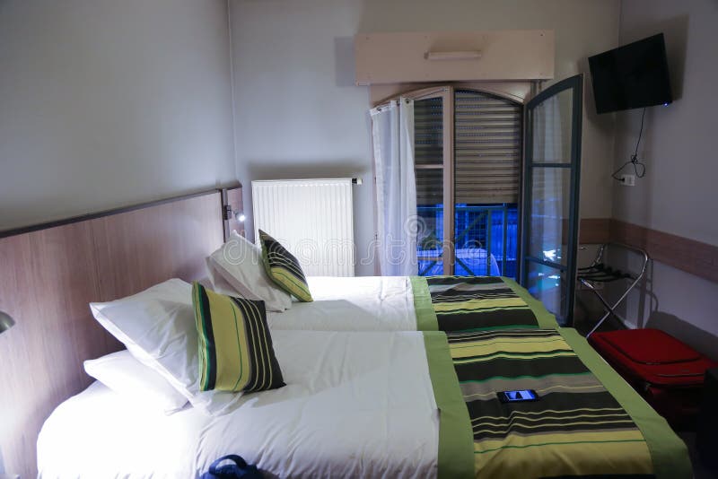 Room interior is in an inexpensive hotel in Lyon in France in the evening. Two beds iare n the foreground and blinds to the floor are against the background of royalty free stock photos