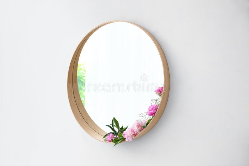 Round mirror with fresh flowers on white wall in room interior royalty free stock image