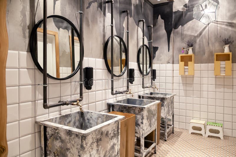 Russia Novosibirsk 2018-11-18 Modern interior of restaurant loft style toilet, square concrete sinks, copper faucet, black stock photos Russia Novosibirsk 2018-11-18 Modern interior of restaurant loft style toilet, square concrete sinks, copper faucet, black stock photos