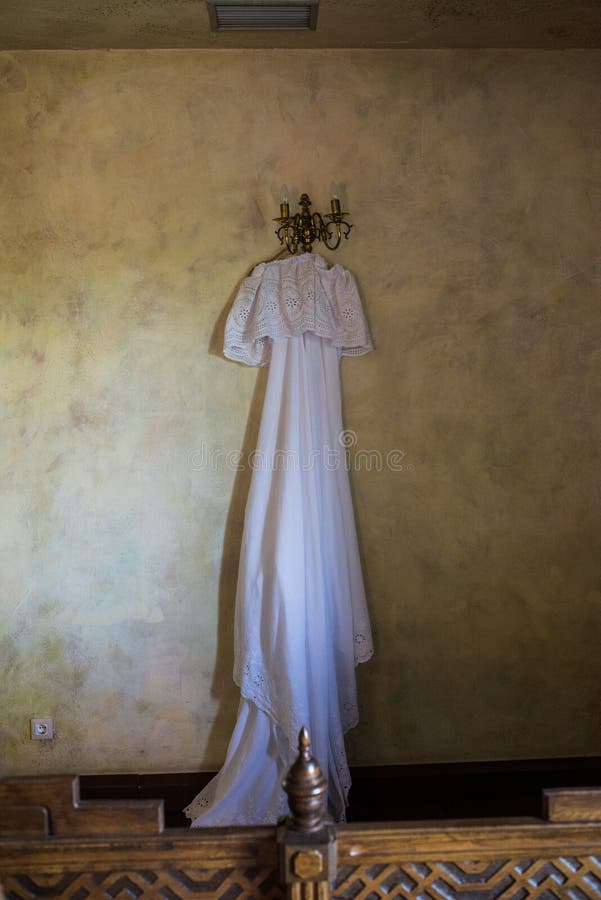 Rustic wedding dress hanging on the chandelier in the room. Beautiful white rustic wedding dress hanging on the chandelier in the room royalty free stock images