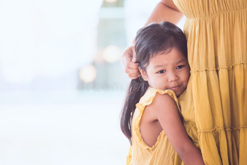 Sad asian child girl hugging her mother leg. In vintage color tone royalty free stock photo