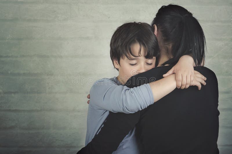 Sad child hugging his mother. On brick background royalty free stock images