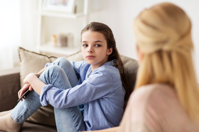 Sad girl with mother sitting on sofa at home. People and family concept - sad girl with mother sitting on sofa at home stock images